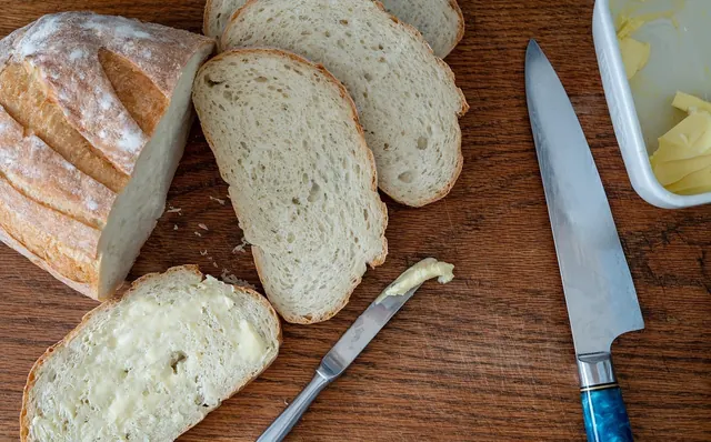 Pão caseiro fatiado, com manteiga passada numa fatia